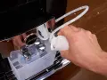 Hand gießt Flüssigkeit in einen Schlauch, um die Kaffeemaschine zu entkalken.
