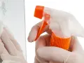 Mit Handschuhen und Sprühflasche werden Kratzer aus Glas poliert. Ein Tuch wischt über die Oberfläche.