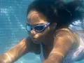 Ein Mädchen schwimmt unter Wasser. Ihre Schwimmbrille ist sauber und klar, damit sie alles sehen kann.