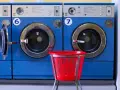 Reihen von blauen Waschmaschinen. Eine rote Wäschekorb steht davor. Ideal für die Waschmaschine reinigen 90 Grad.
