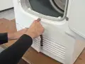 Hände prüfen die Gummidichtung der Trocknertür. Vielleicht ist das der Grund, warum der trockner trocknet nicht richtig.