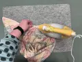 Ein kleines Bügeleisen zum Nähen glättet Stoff mit Blattmuster auf einer Filzmatte.