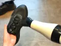 Schwarze Turnschuhe trocknen mit einem Föhn. Ein Paar nasse Schuhe wird mit einem Föhn getrocknet, um sie schnell wieder einsatzbereit zu machen.