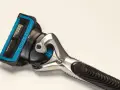 Ein Rasierer mit blauer Kappe und mehreren Klingen. Die Rasierklingen reinigen sanft die Haut für eine glatte Rasur.