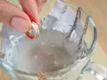 Ein Ring mit kleinen Steinen wird in eine Schüssel mit Wasser und Aluminiumfolie getaucht, um Schmuck zu reinigen.