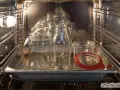 Mehrere leere Gläser und Flaschen stehen auf einem Blech im Backofen, bereit zum Sterilisieren.
