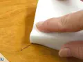Mit einem weißen Schwamm wird ein Permanentmarker-Strich auf Holz entfernt.
