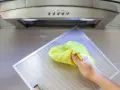 Hand reinigt Dunstabzugshaube mit gelbem Tuch.