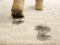 Schmutzige Stiefel hinterlassen Spuren auf dem hellen Teppich. Zeit für den outdoor teppich reinigen.