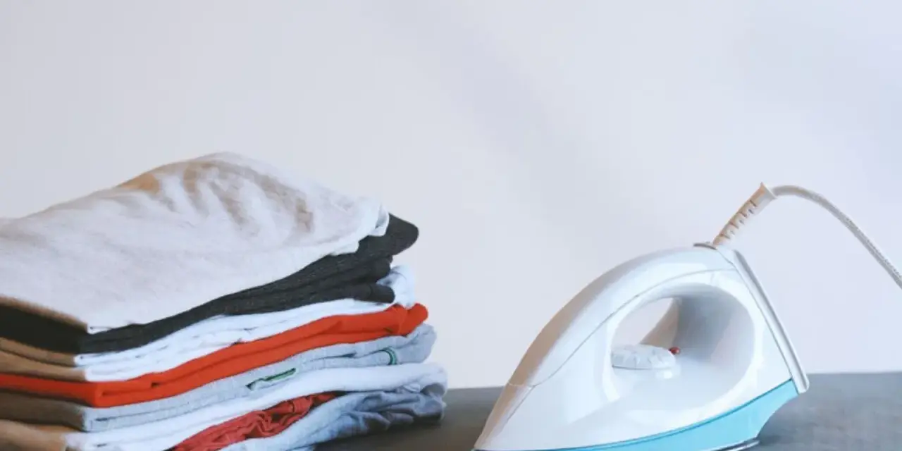 Ein Stapel bunter Kleidung neben einem weißen, easy home bügeleisen.