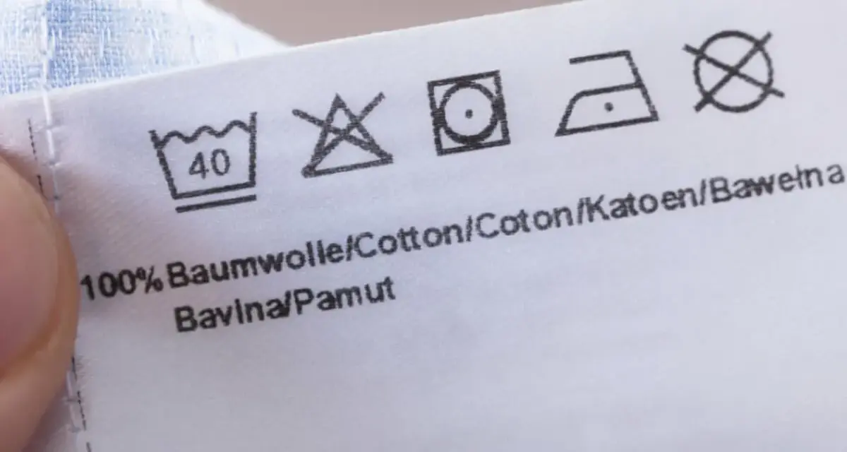 Pflegesymbol: Nicht im Trockner trocknen. Das Etikett zeigt auch Wasch- und Bügelsymbole für 100% Baumwolle.