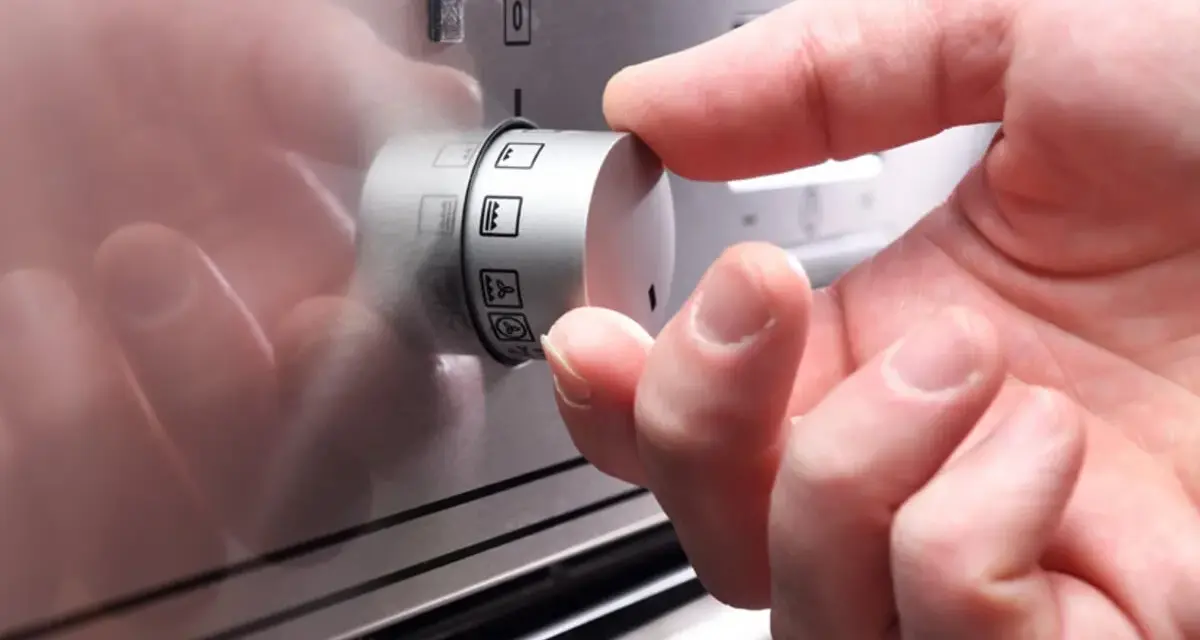Hand dreht Regler mit Backofen Symbolen.