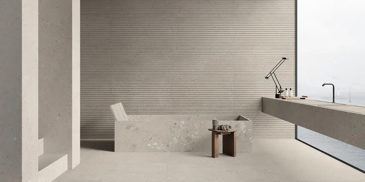 Modernes Bad mit Wanne und Waschtisch. Die geriffelten Wandfliesen und Terrazzo-Bodenfliesen sind leicht zu reinigen.