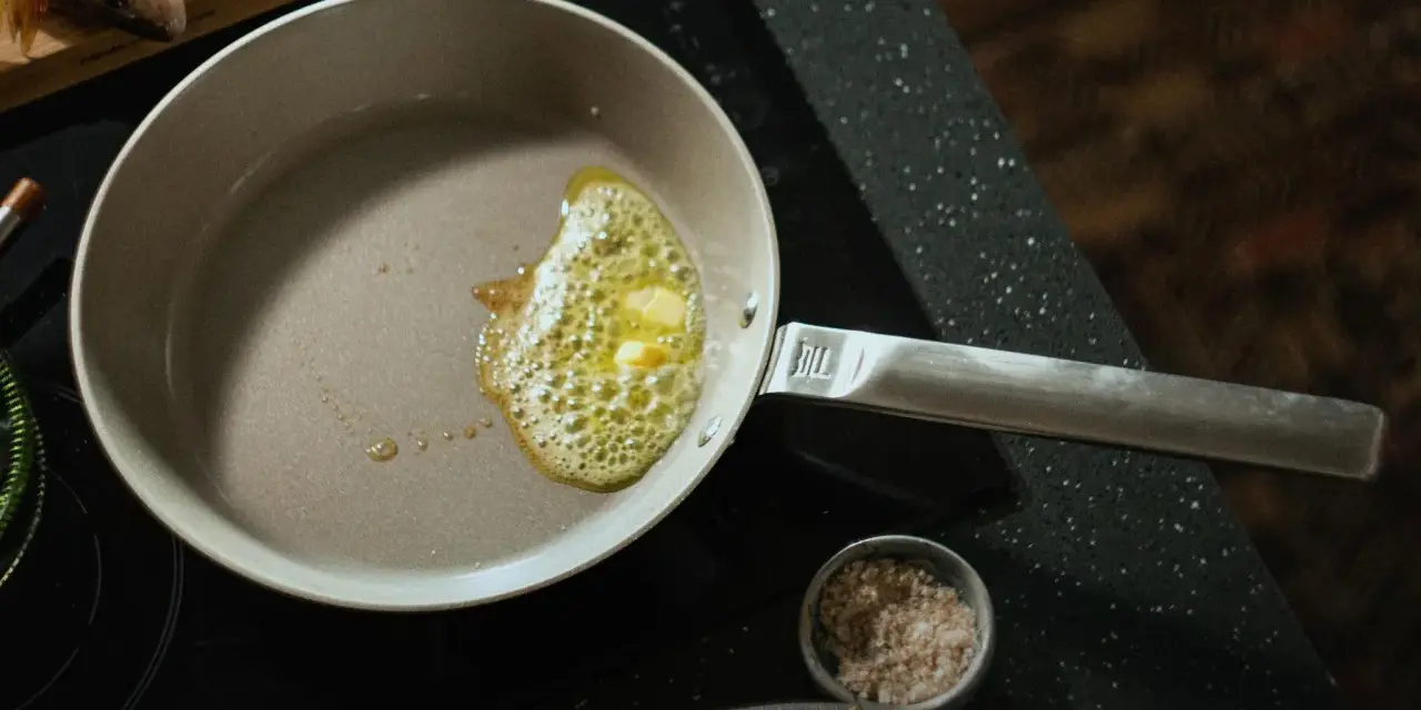 Butter schmilzt in einer beschichteten Pfanne, bereit für das Braten von Fisch.