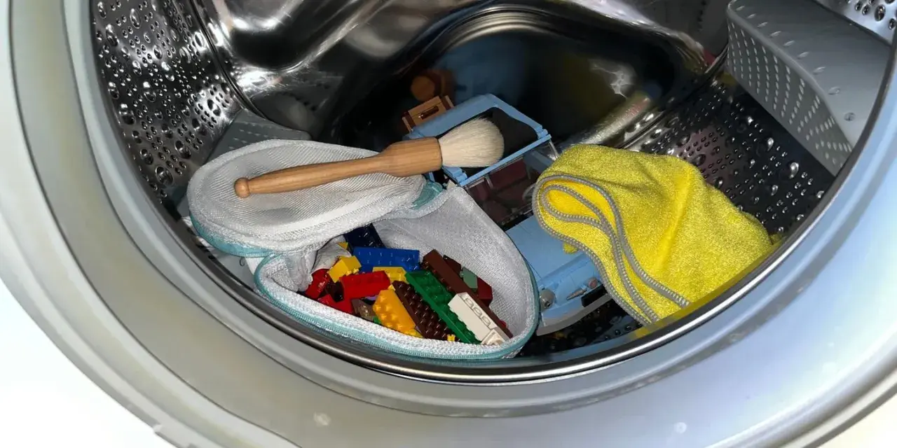 Bunte Lego-Steine in einem Wäschenetz, ein Spielzeugauto und ein gelbes Tuch in einer Waschmaschinentrommel.