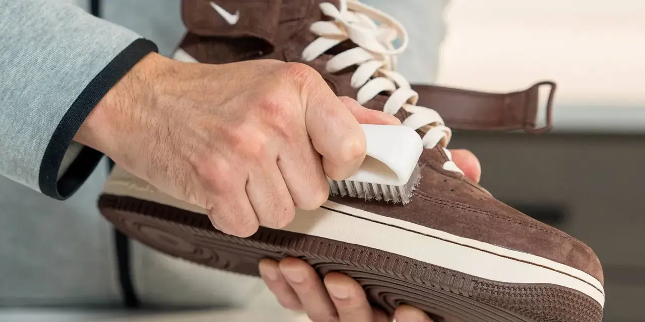 Hände reinigen braune Wildleder Schuhe mit einer Bürste. So werden die Lieblingssneaker wieder wie neu.