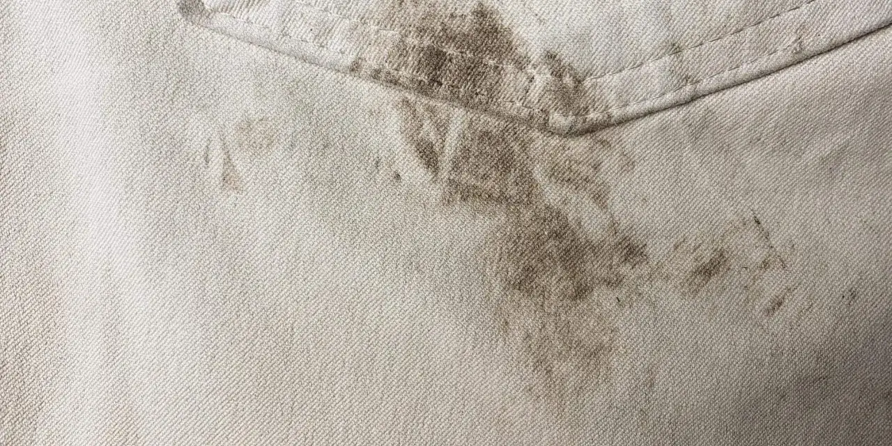 Schmutzige helle Hose mit dunklen Flecken. Tipps, wie man Fettflecken aus Kleidung entfernen kann, sind hier gefragt.