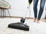 Eine Person saugt mit einem Sapur Teppichreiniger einen weißen Teppich ab. Die Anleitung ist hier nicht sichtbar, aber das Ergebnis wird sauber sein.