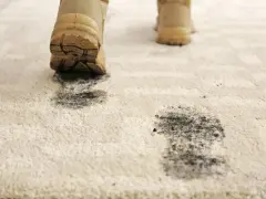 Schmutzige Stiefel hinterlassen Spuren auf dem hellen Teppich. Zeit für den outdoor teppich reinigen.