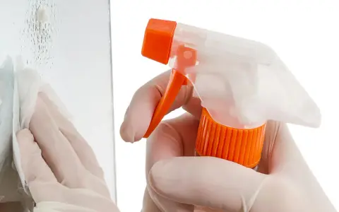 Mit Handschuhen und Sprühflasche werden Kratzer aus Glas poliert. Ein Tuch wischt über die Oberfläche.