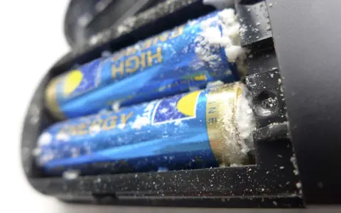 Ausgelaufene Batterie reinigen: Weißer Belag auf Batterien im Batteriefach.