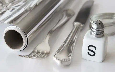 Silber reinigen: Alufolie, Salzstreuer und Besteck liegen bereit für die Hausmittel-Reinigung.