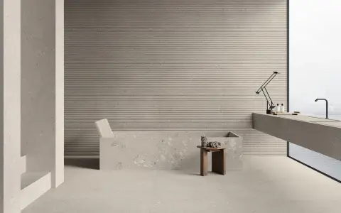 Modernes Bad mit Wanne und Waschtisch. Die geriffelten Wandfliesen und Terrazzo-Bodenfliesen sind leicht zu reinigen.