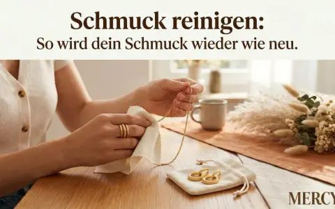 Hände polieren eine goldene Halskette und Ringe mit einem Tuch. So wird Modeschmuck reinigen zum Kinderspiel.