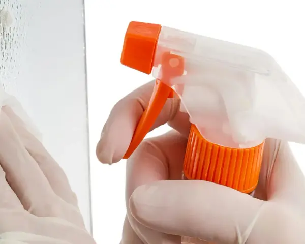 Mit Handschuhen und Sprühflasche werden Kratzer aus Glas poliert. Ein Tuch wischt über die Oberfläche.