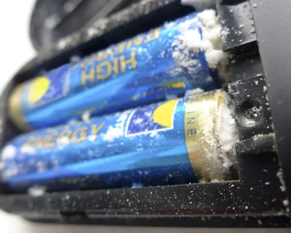Ausgelaufene Batterie reinigen: Weißer Belag auf Batterien im Batteriefach.