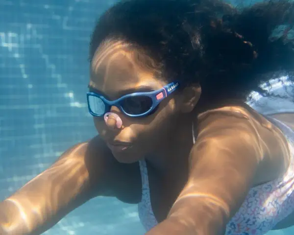 Ein Mädchen schwimmt unter Wasser. Ihre Schwimmbrille ist sauber und klar, damit sie alles sehen kann.