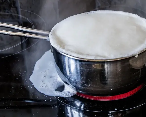 Milch kocht über und läuft auf den Herd. Das bedeutet, der Herd muss gereinigt werden.