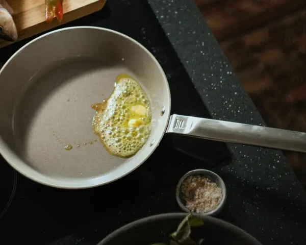 Butter schmilzt in einer beschichteten Pfanne, bereit für das Braten von Fisch.