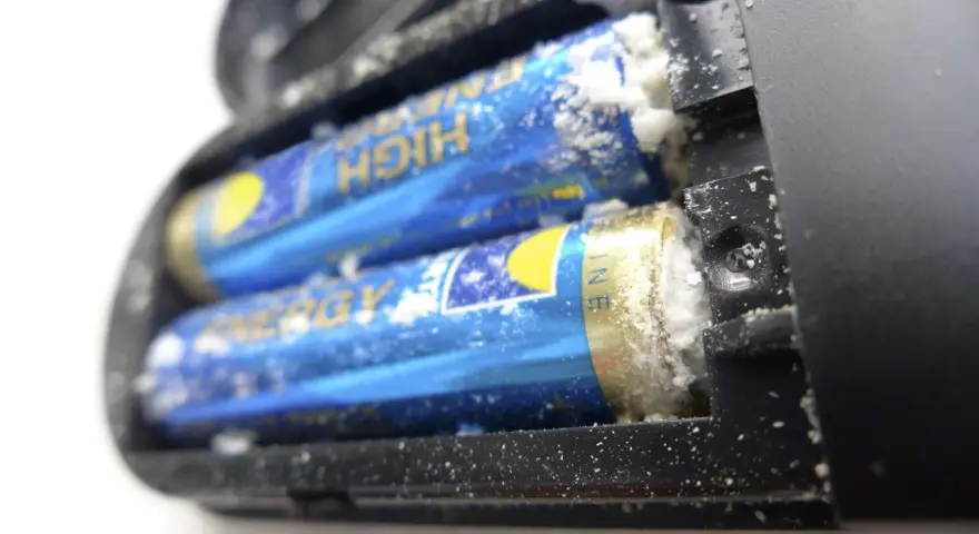 Ausgelaufene Batterie reinigen: Weißer Belag auf Batterien im Batteriefach.