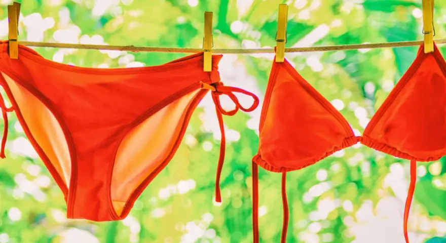 Roter Bikini trocknet an der Wäscheleine. Nach dem **Bikini waschen** duftet er frisch in der Sonne.