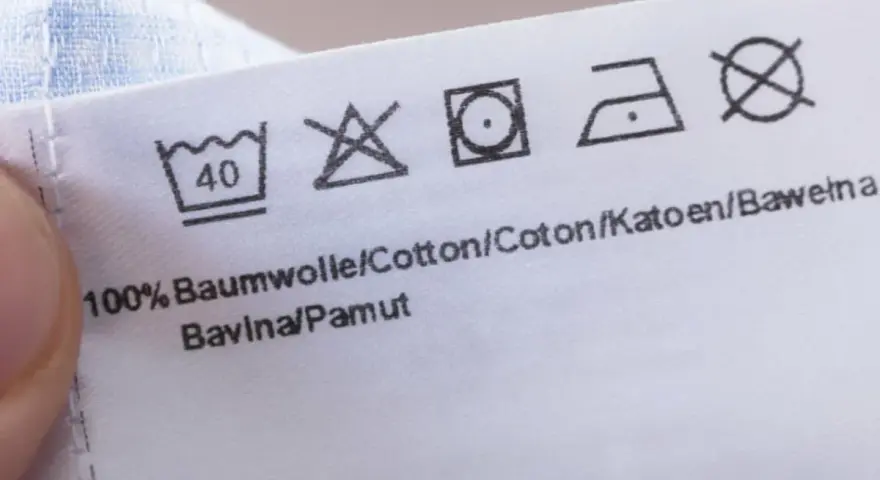 Pflegesymbol: Nicht im Trockner trocknen. Das Etikett zeigt auch Wasch- und Bügelsymbole für 100% Baumwolle.