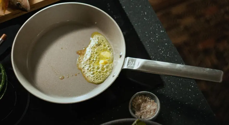 Butter schmilzt in einer beschichteten Pfanne, bereit für das Braten von Fisch.