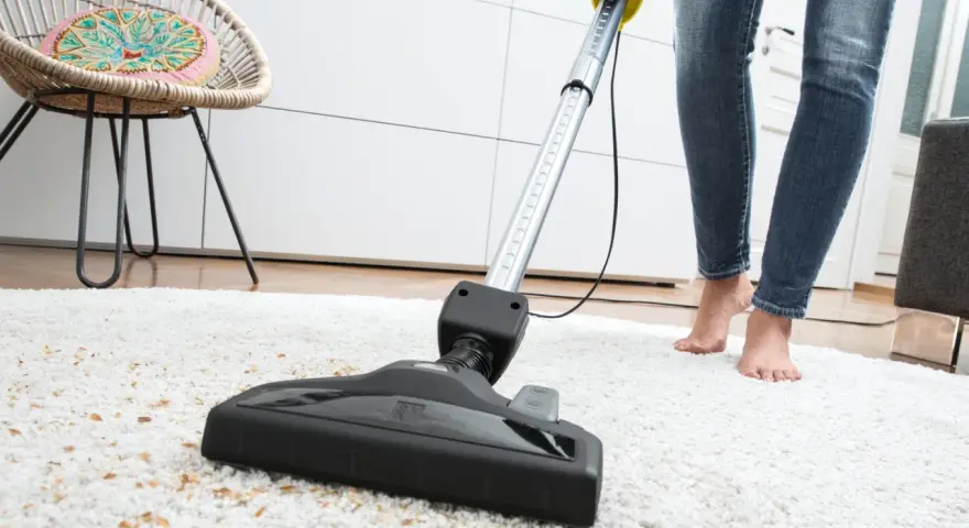 Eine Person saugt mit einem Sapur Teppichreiniger einen weißen Teppich ab. Die Anleitung ist hier nicht sichtbar, aber das Ergebnis wird sauber sein.