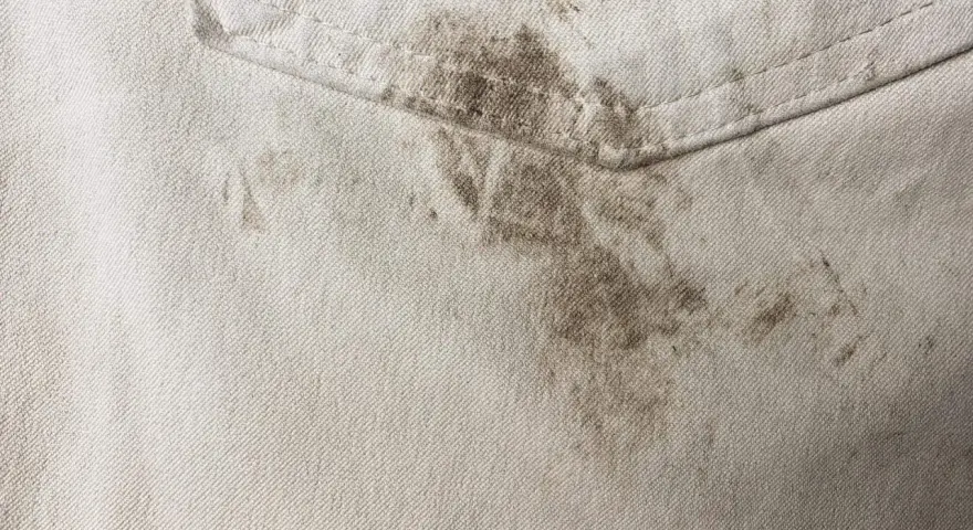Schmutzige helle Hose mit dunklen Flecken. Tipps, wie man Fettflecken aus Kleidung entfernen kann, sind hier gefragt.