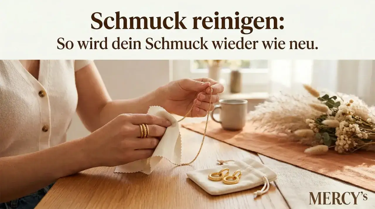 Hände polieren eine goldene Halskette mit einem Tuch. Daneben liegen goldene Ohrringe in einem Beutel. So einfach ist Schmuck reinigen!