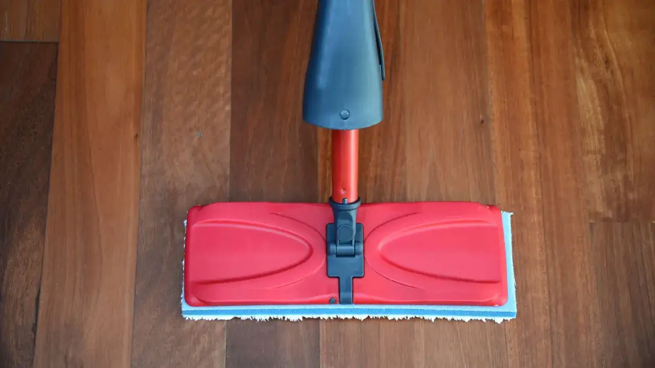 Ein roter Wischmopp auf einem Holzfu&szlig;boden. Perfekt f&uuml;r das Laminat reinigen Hausmittel.