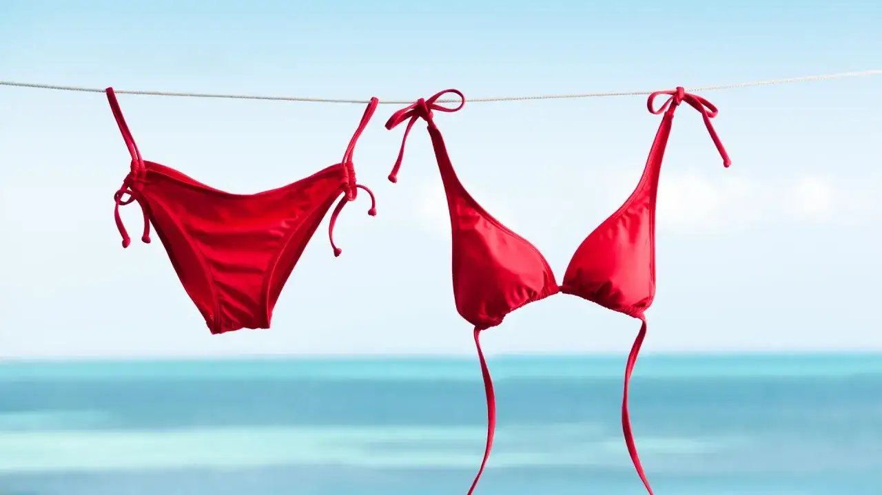 Roter Bikini trocknet an der Leine &uuml;ber dem Meer. Nach dem Bikini waschen bereit f&uuml;r den n&auml;chsten Strandtag.