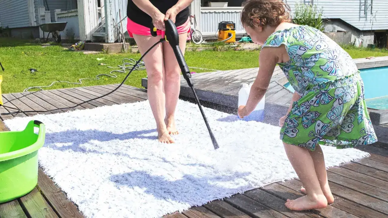 Kind hilft beim outdoor teppich reinigen mit Hochdruckreiniger auf Holzdeck.