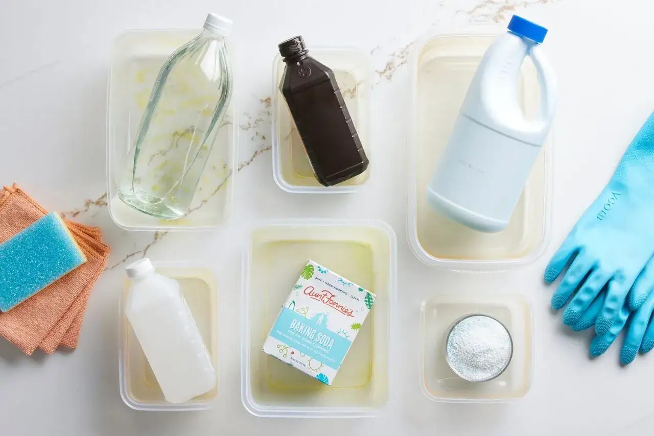 Vergilbtes Kunststoff reinigen: Essig, Wasserstoffperoxid, Bleichmittel und Backpulver liegen bereit. Blaue Handschuhe und T&uuml;cher warten.