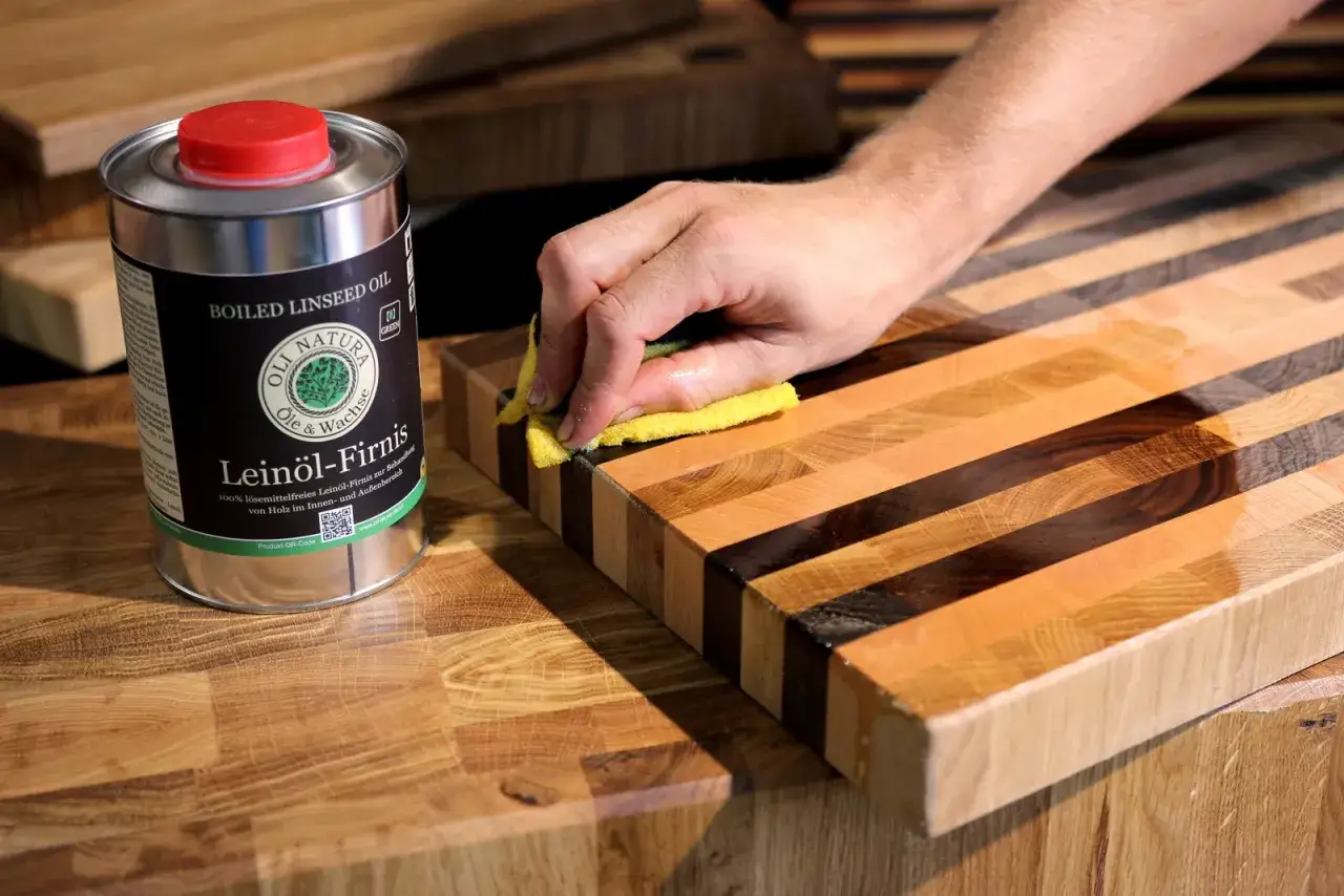 Holz entfetten mit Lein&ouml;l-Firnis. Eine Hand reibt mit einem gelben Schwamm &uuml;ber ein Holzbrett, um es zu pflegen.