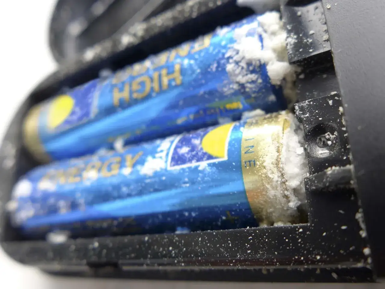 Zwei Batterien mit wei&szlig;em Auswurf im Batteriefach. Zeit, ausgelaufene Batterie reinigen.