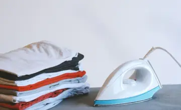 Ein Stapel bunter Kleidung neben einem weißen, easy home bügeleisen.