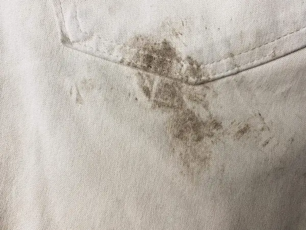 Schmutzige helle Hose mit dunklen Flecken. Tipps, wie man Fettflecken aus Kleidung entfernen kann, sind hier gefragt.